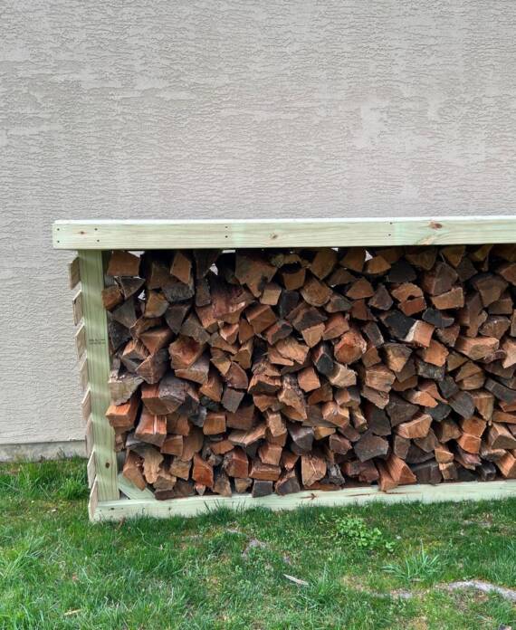 Handyman building wooden firewood storage structure in Hampton, NH