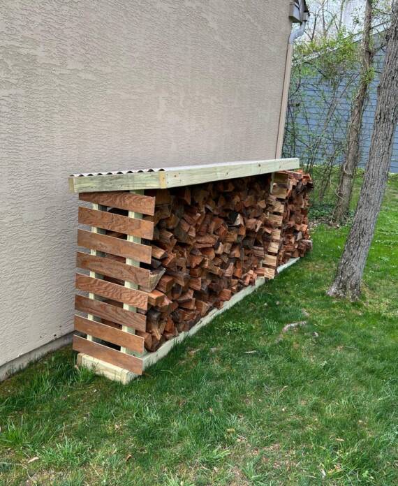 Handyman building wooden firewood storage structure in Hampton, NH