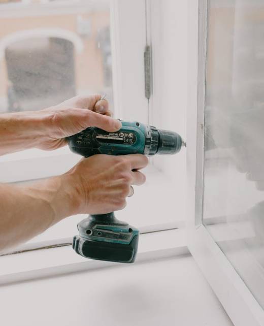 Handyman repairing a window with a drill in Hampton, NH by Anchor Point Repair